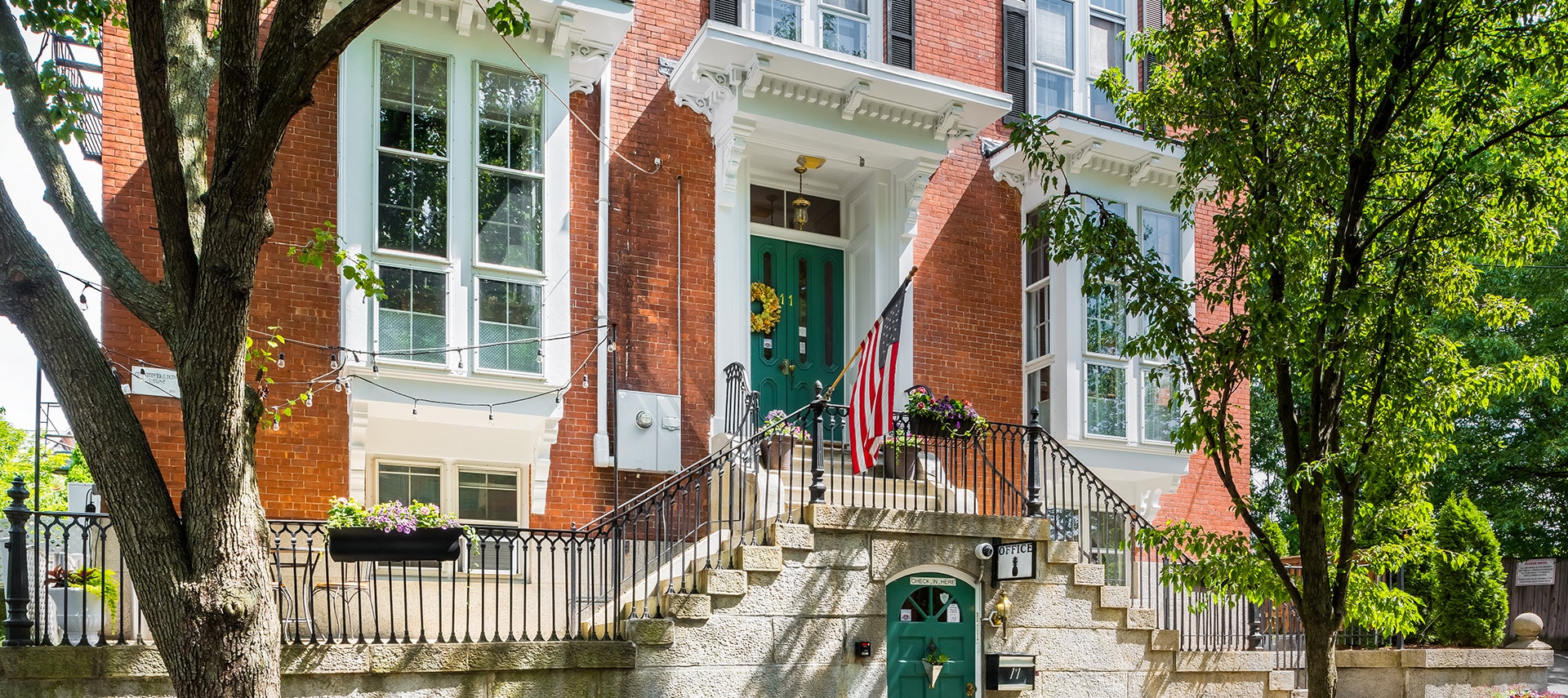 Brick exterior with black railings and sage green doors.