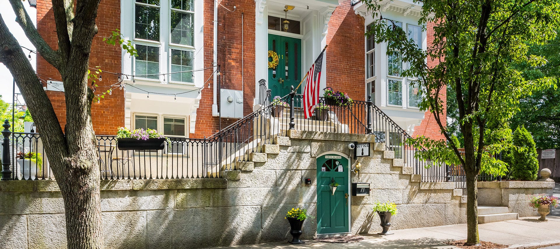 Two sage green entryway doors framed by a beautiful red brick exterior.