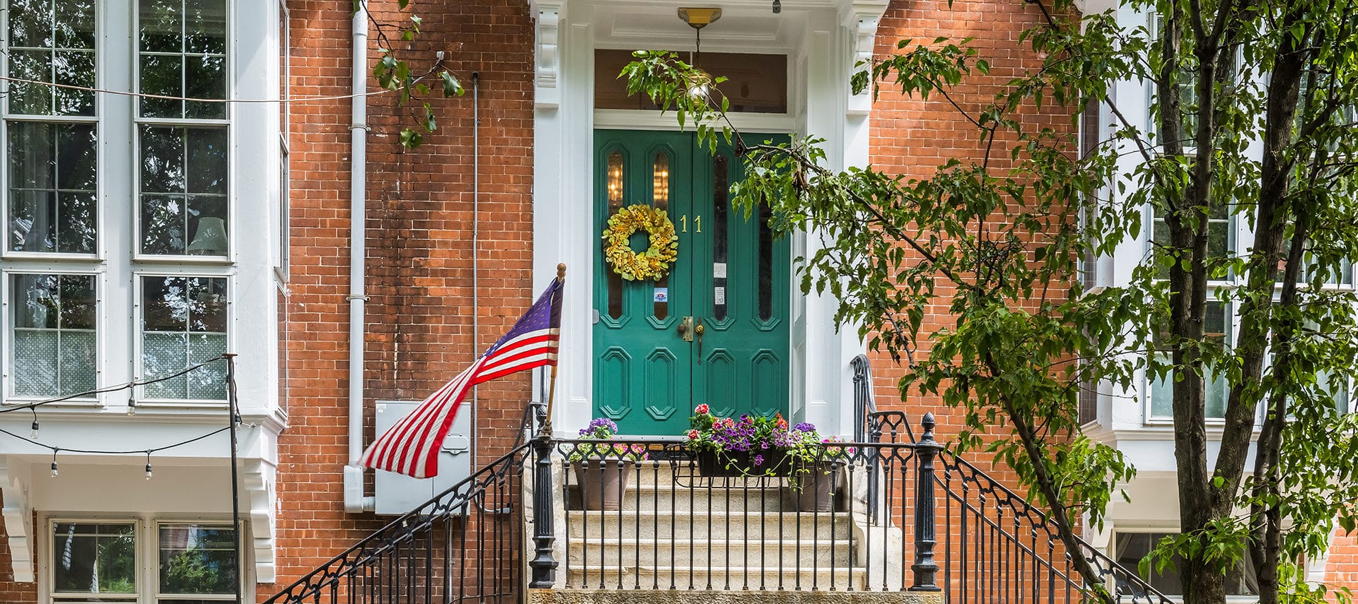 Sage green entryway doors framed by beautiful red brick exterior.