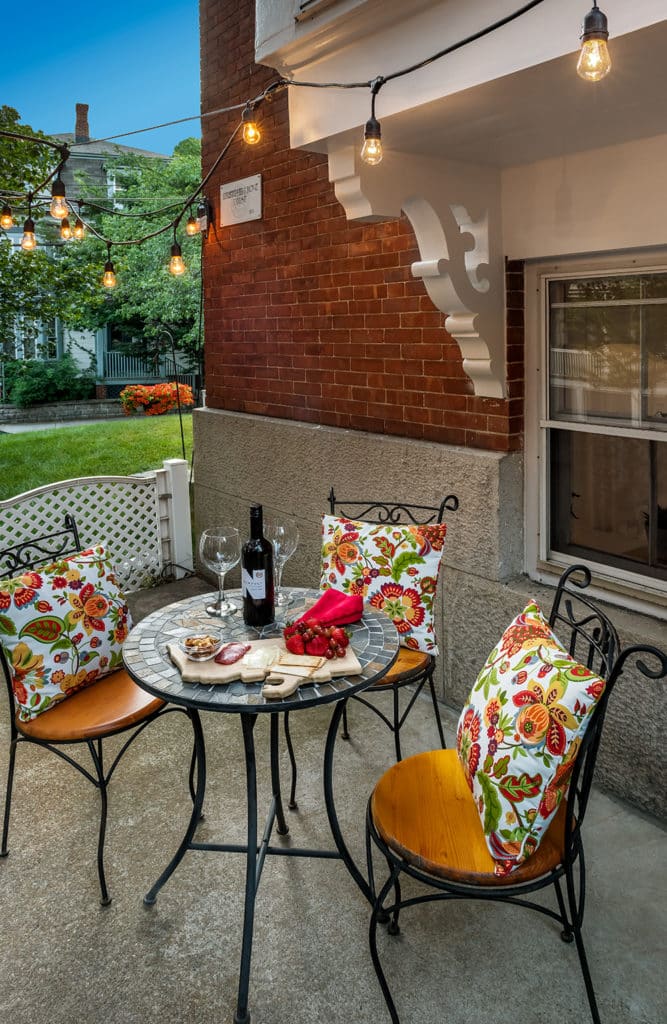 Patio table featuring a bottle of red wine and a charcuterie board.