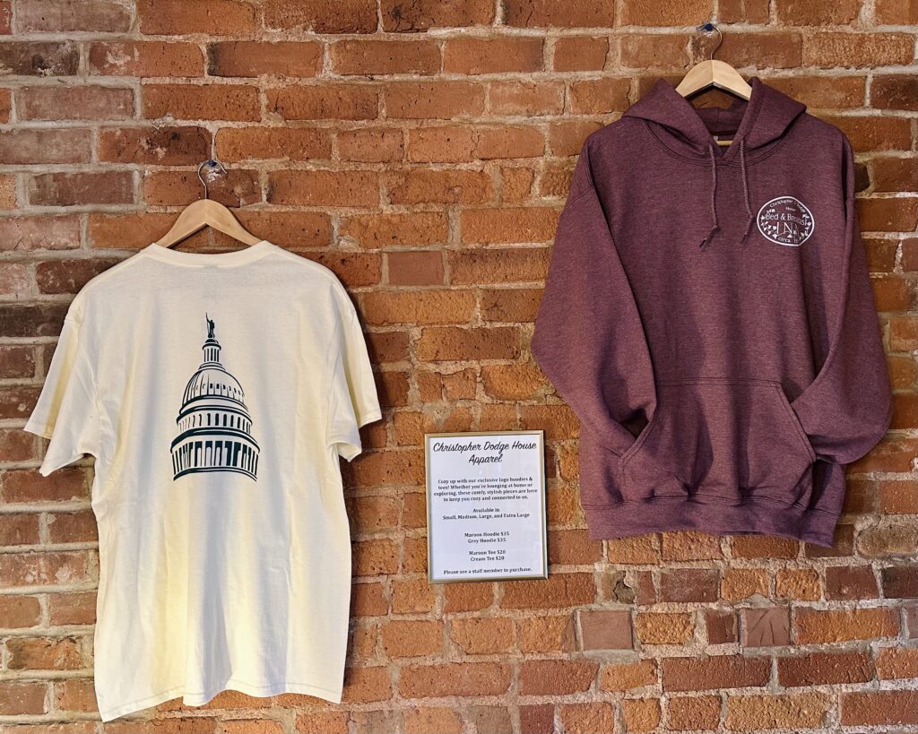 A hoodie and t-shirt hanging on a red brick wall.
