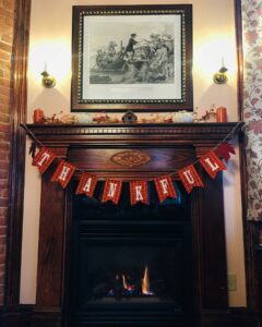 Thankful banner hanging from a wooden fireplace mantle.