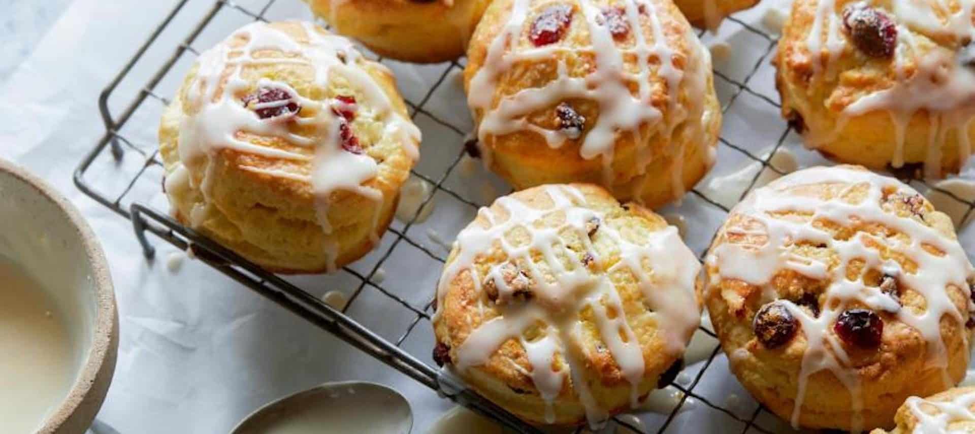Buttery cranberry orange scones drizlled with icing placed on a cooling rack.