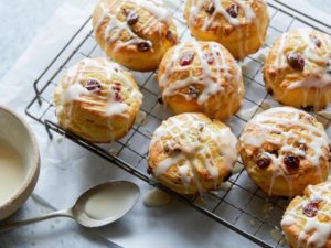 Buttery cranberry orange scones drizlled with icing placed on a cooling rack.
