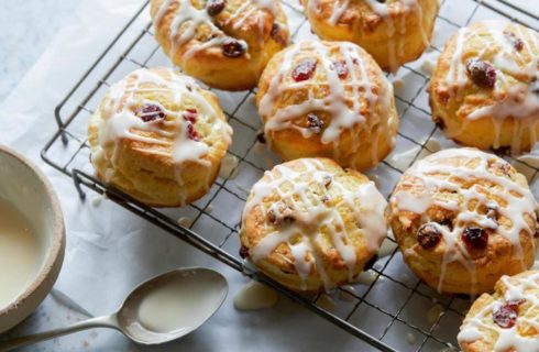 Buttery cranberry orange scones drizlled with icing placed on a cooling rack.