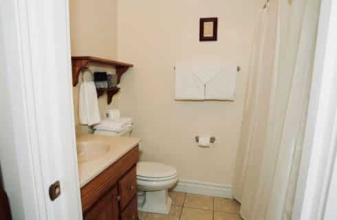 White linen walls bathroom with wooden vanity and white shower curtain.