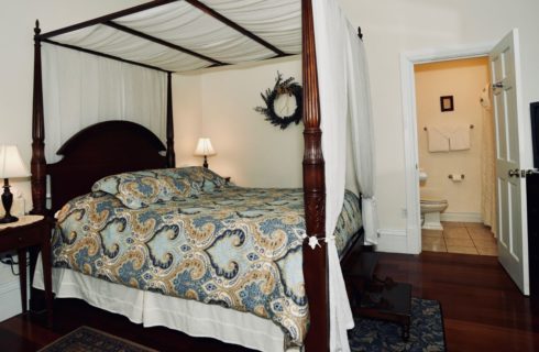 Queen bed canopied in white with a blue patterned comforter.