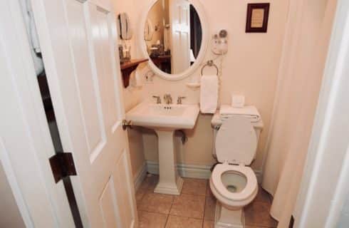 Bathroom with white with a pedestal sink, toilet and white shower curtain.
