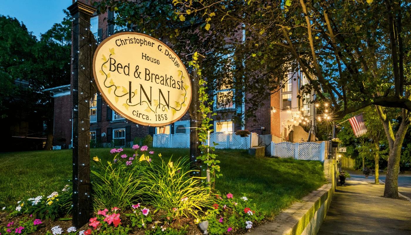 Christopher Dodge House sign lit up by flood lights flanked by beautiful greenery.