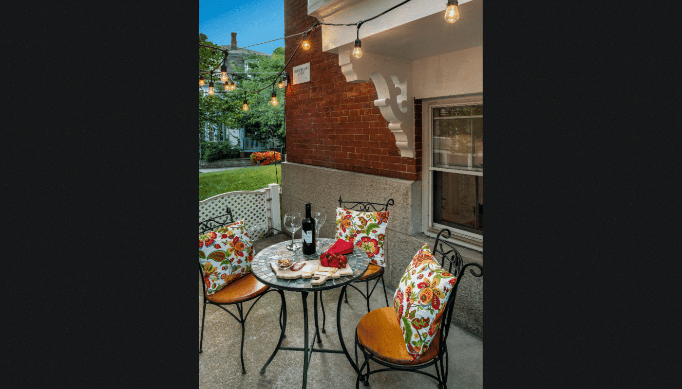 Patio table featuring a bottle of red wine and a charcuterie board.