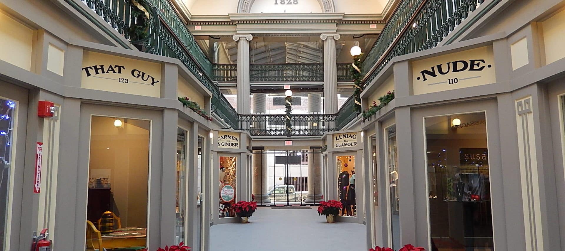 An indoor shopping mall corridor lined with holiday poinsettias.