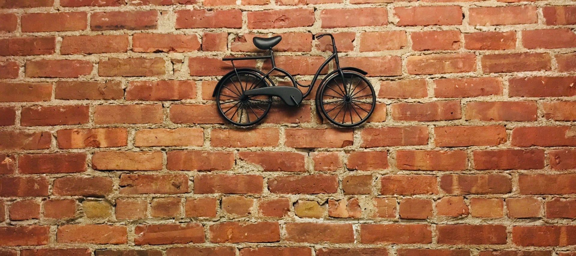 Red brick wall with a black metal bike.