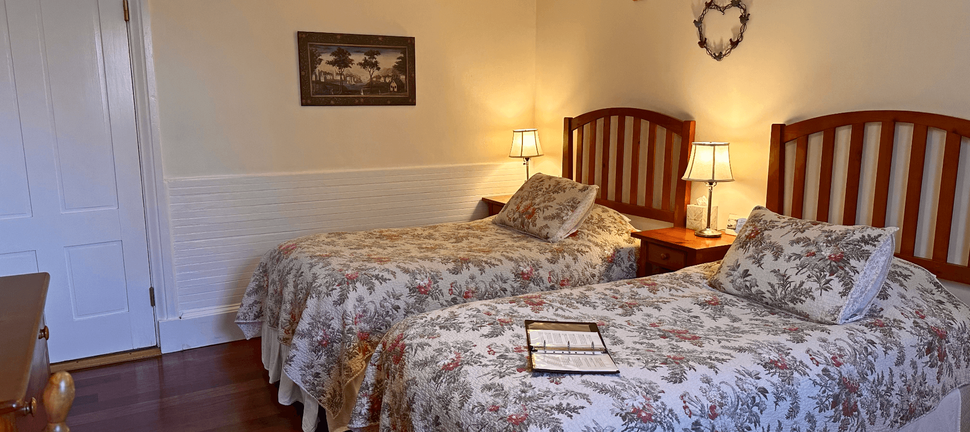 A room with two beds and bed side tables with lamps.