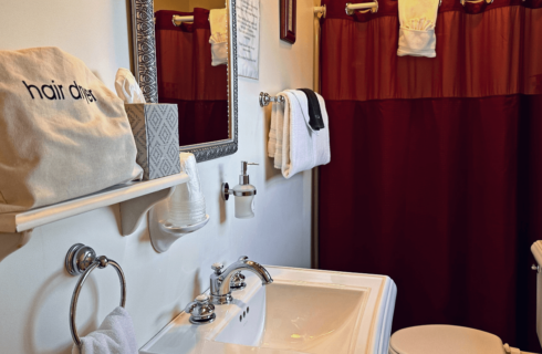 A bathroom with a sink, mirror, toilet, and shower.