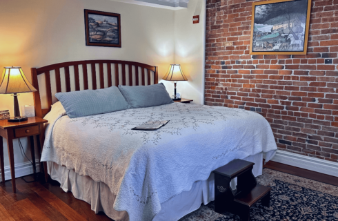 A room with a bed and side tables with lamps.