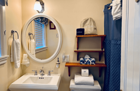 A bathroom with a sink, mirror, toilet, and shower.