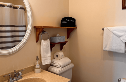 A bathroom with a sink, mirror, and a toilet.