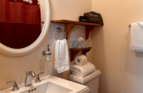 A bathroom with a sink, mirror, and toilet.