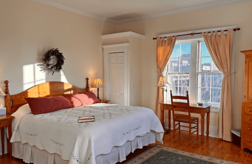 A room with a bed, armoire, and desk with chair.