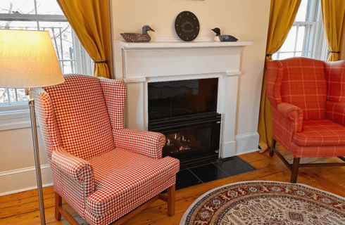 A room with a fireplace and two chairs.