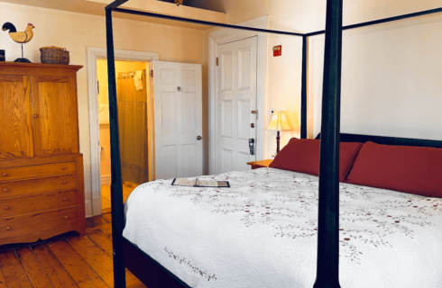 A four-poster bed adorned with an embroidered quilt.