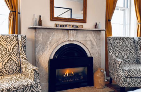 Two chairs flanking a marble fireplace.