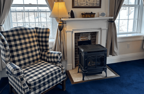 A room with a chair and wood stove.