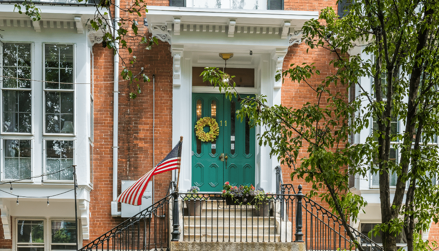 Main entryway with sage green doors framed by a red brick exterior.