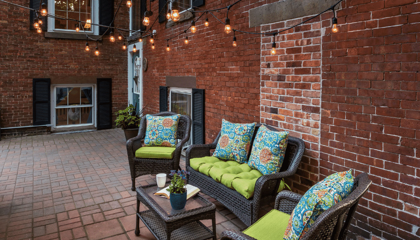 Outdoor patio featuring wicker furniture and bright green cushions with string lights overhead.