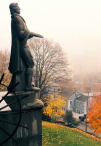 A large statue of Roger Williams situated on a hill overlooking Providence on a foggy fall day.