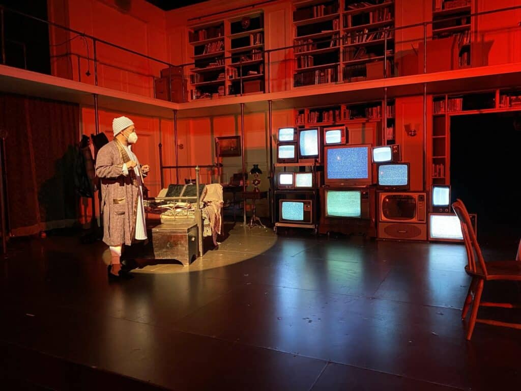 A gentleman on stage with many televisions in the background.