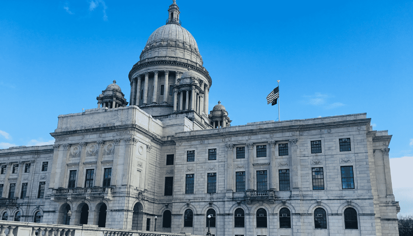 Large granite building with lots of windows with a bright blue sky in the background.