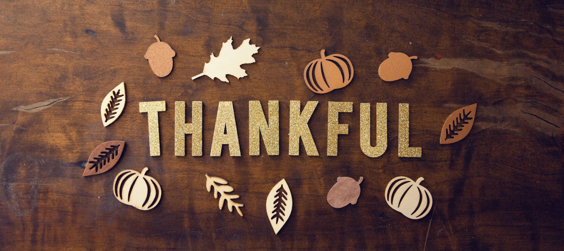Wooden table with decorative gold leaves and the word thankful spelled out.