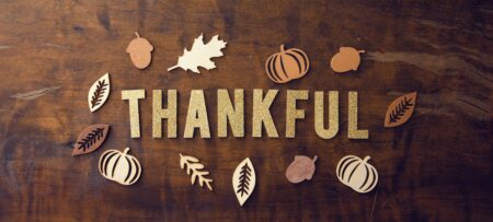 Wooden table with decorative gold leaves and the word thankful spelled out.