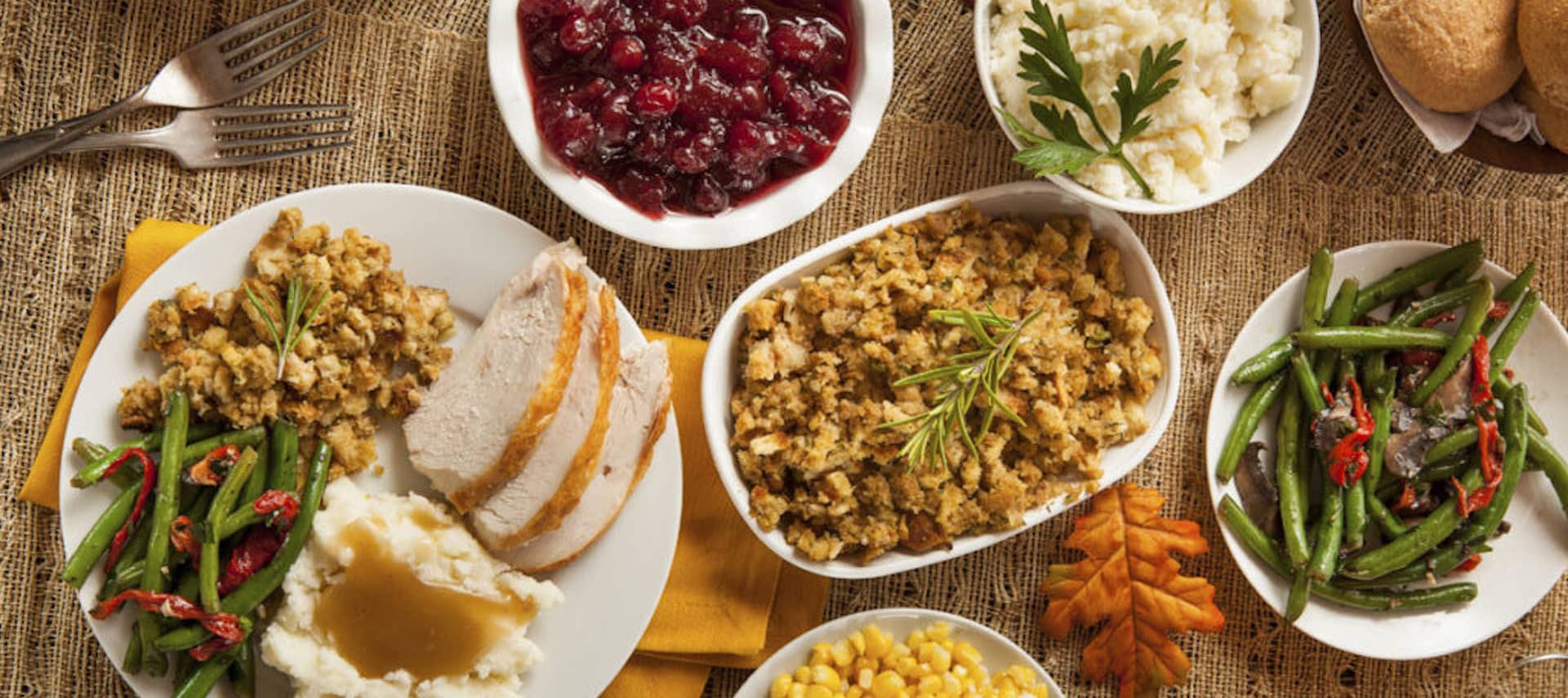 Table with plates full of vegetables and turkey for Thanksgiving Dinner.