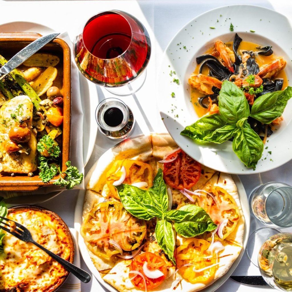 A delicious spread of Italian dishes of food with a glass of red wine.