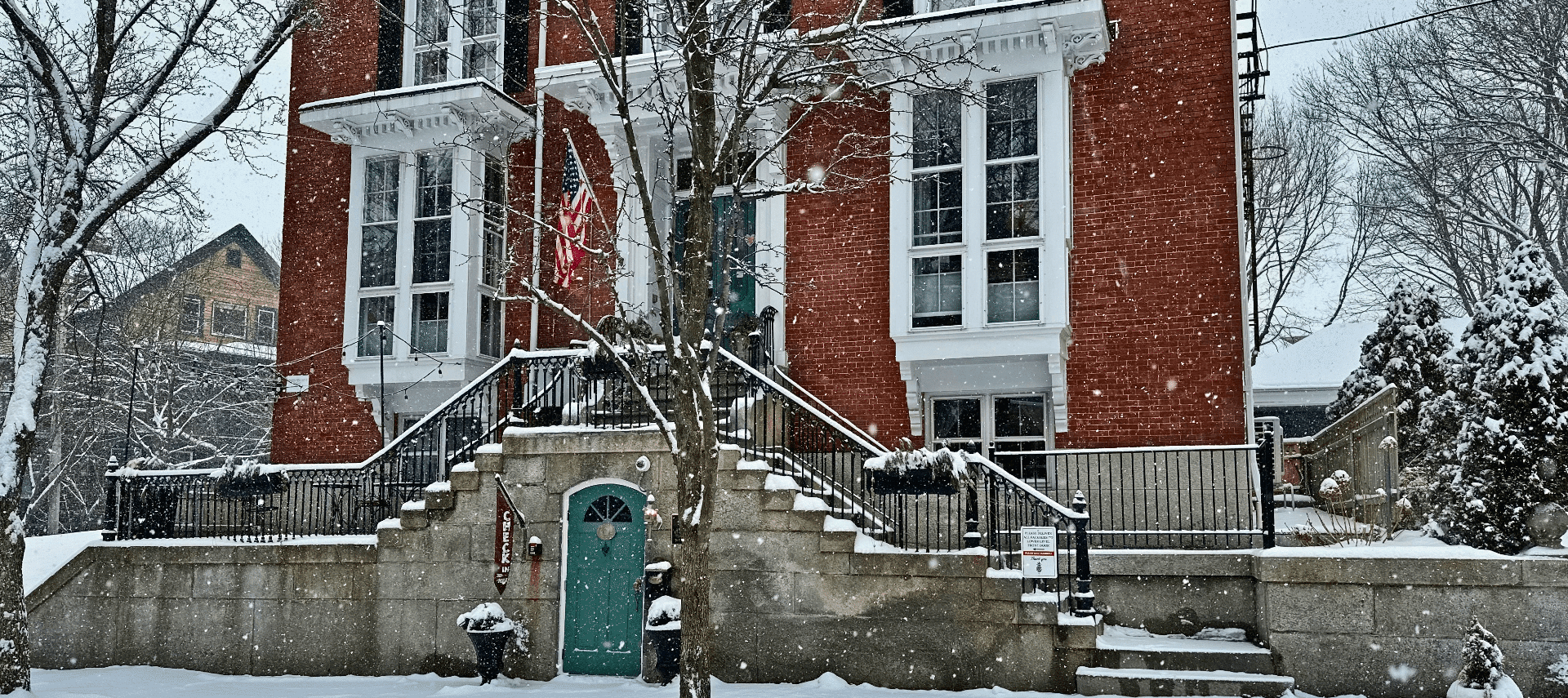 Snow falling with a large brick building in the foreground.