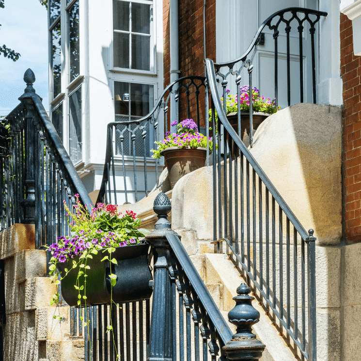 Bright beautiful flower boxes hanging on a black railing outside.