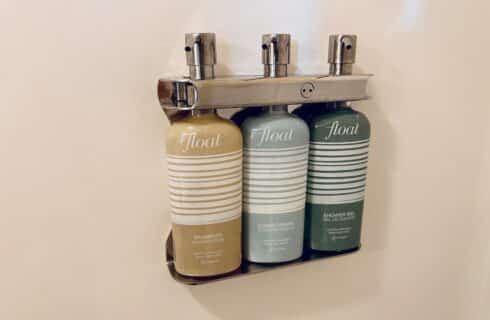 3 wall mounted soap pumps; shampoo, conditioner, and shower gel.