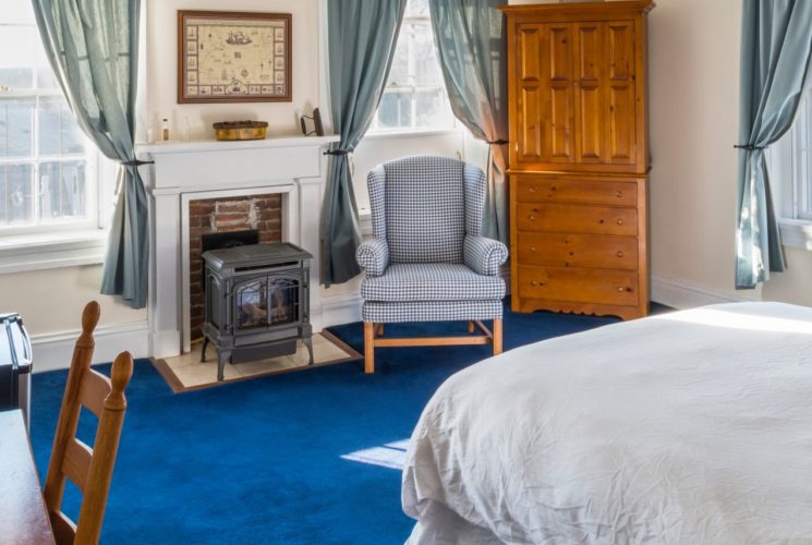 Charming bedroom with a queen bed, small wood stove and two big bright windows.