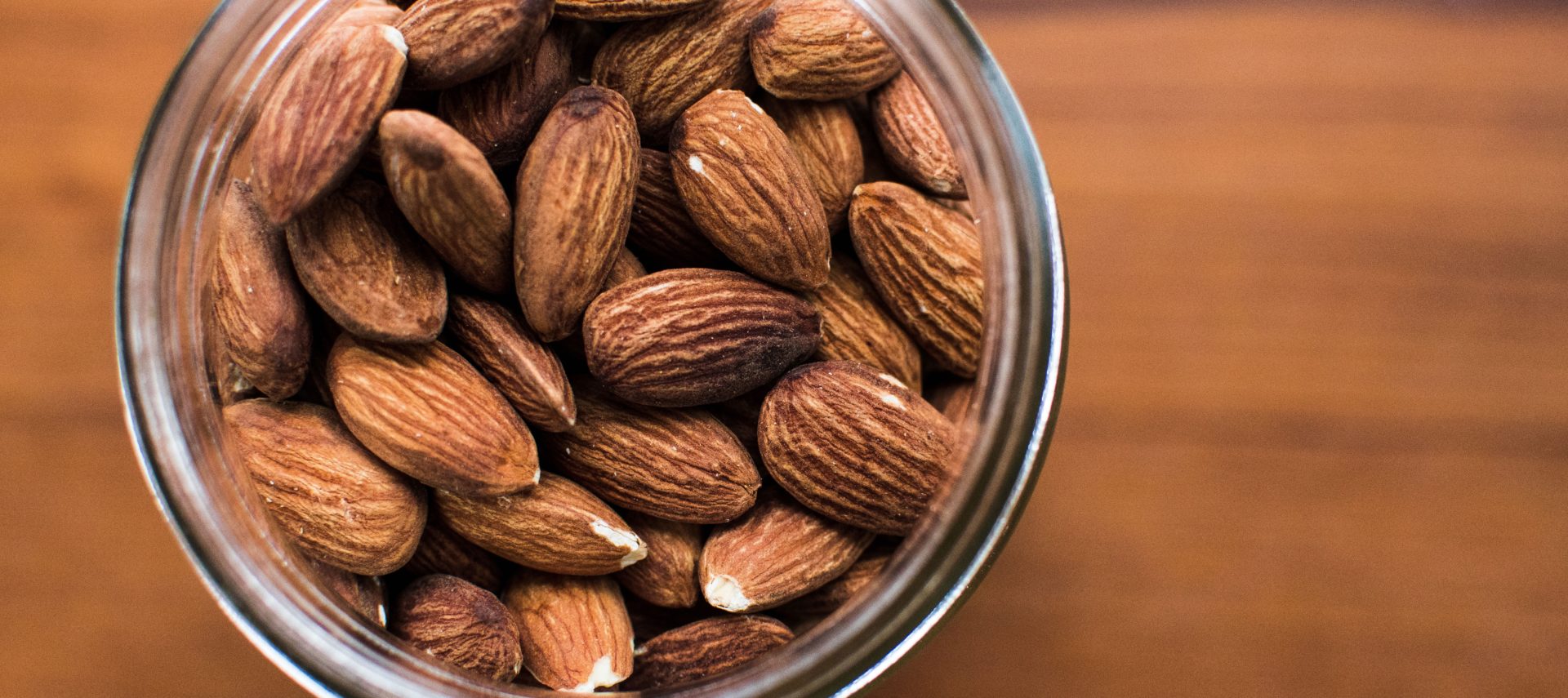 Almonds in a glass jar placed on a tabletop.