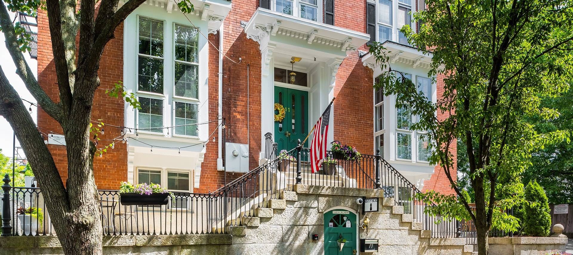 Brick exterior with black railings and sage green doors.
