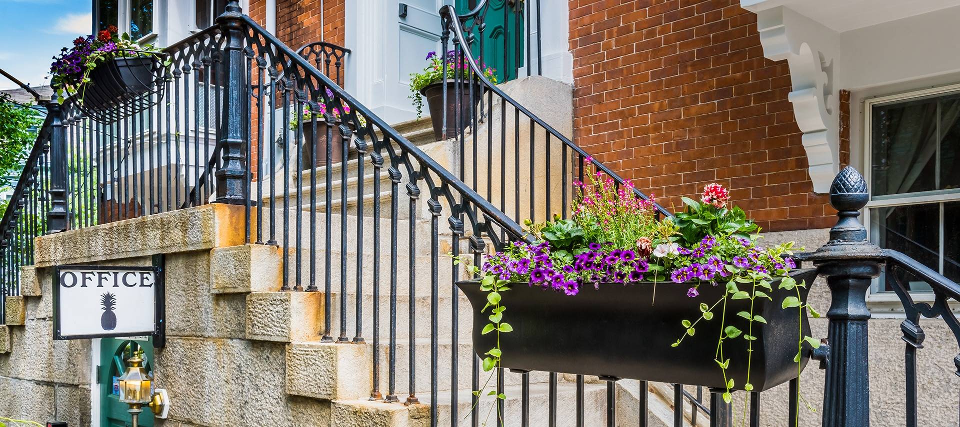 Beautiful flower boxes hanging on a black railing above the office entryway.