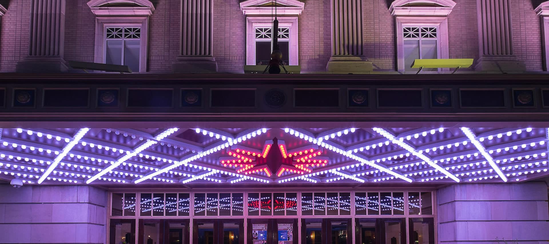 Bright neon white and red lighting of the Veterans Memorial Auditorium exterior .